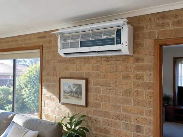 Clean split system with open front panel and visible filters on a brick living room wall in Redwood Park