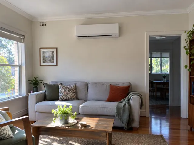 Wall-mounted split system above a sofa in a bright living room with timber floors in Tea Tree Gully